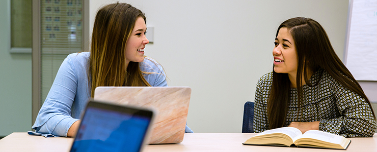 two students talking at table